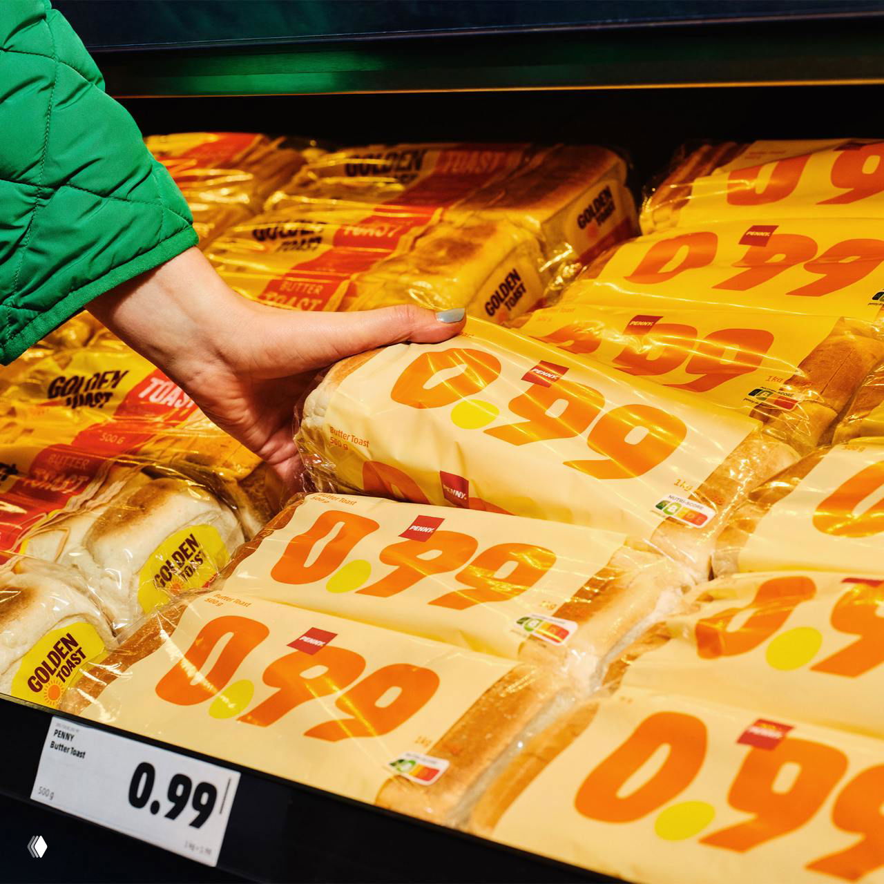 Полиция полок в магазине: упаковки хлеба с крупными оранжевыми цифрами цены 0.29, одна упаковка берётся рукой покупателя.