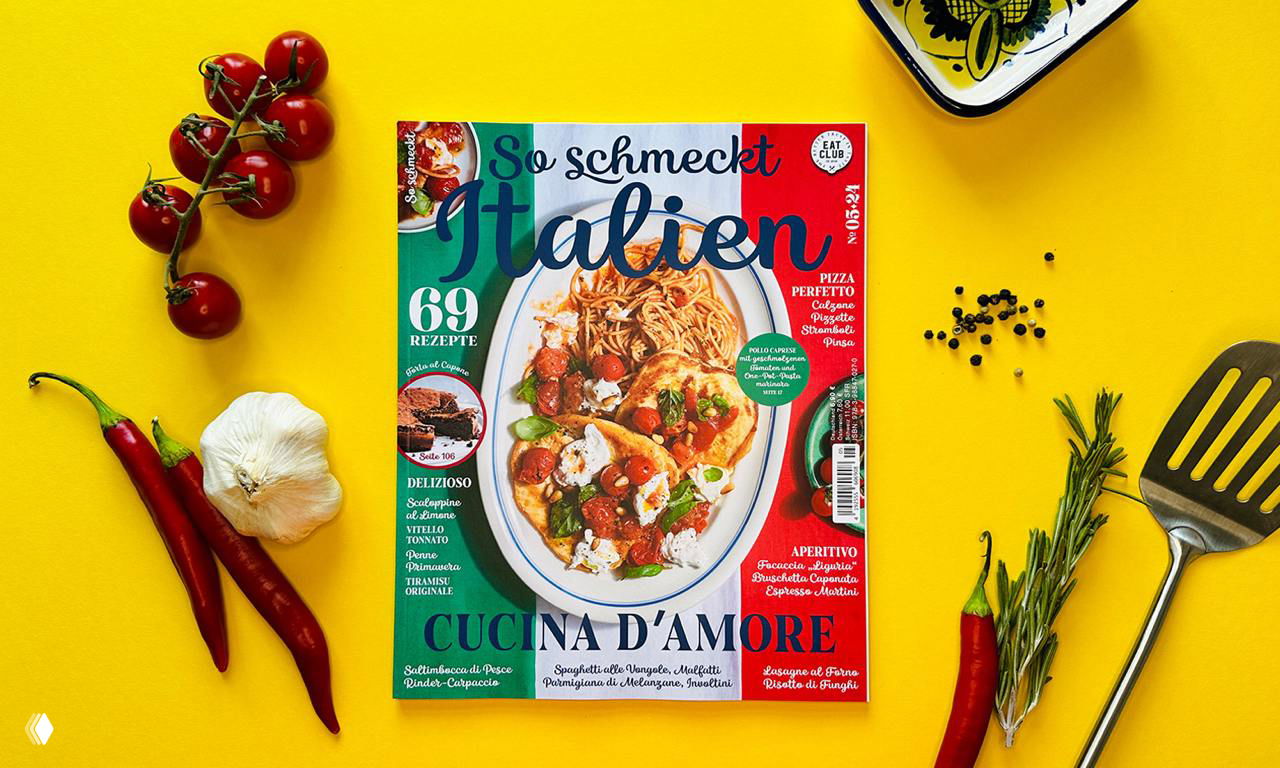 Обложка журнала на жёлтом фоне: тарелка пасты на центре, рядом помидоры, чеснок, чили и кухонные приборы как реквизит к иллюстрациям.