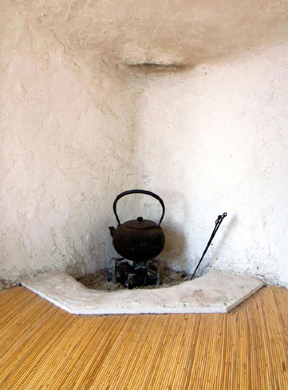 Интерьерный кадр: очаг и чайник в нише из белой глины, плетёный пол, традиционная японская атмосфера чайной комнаты.