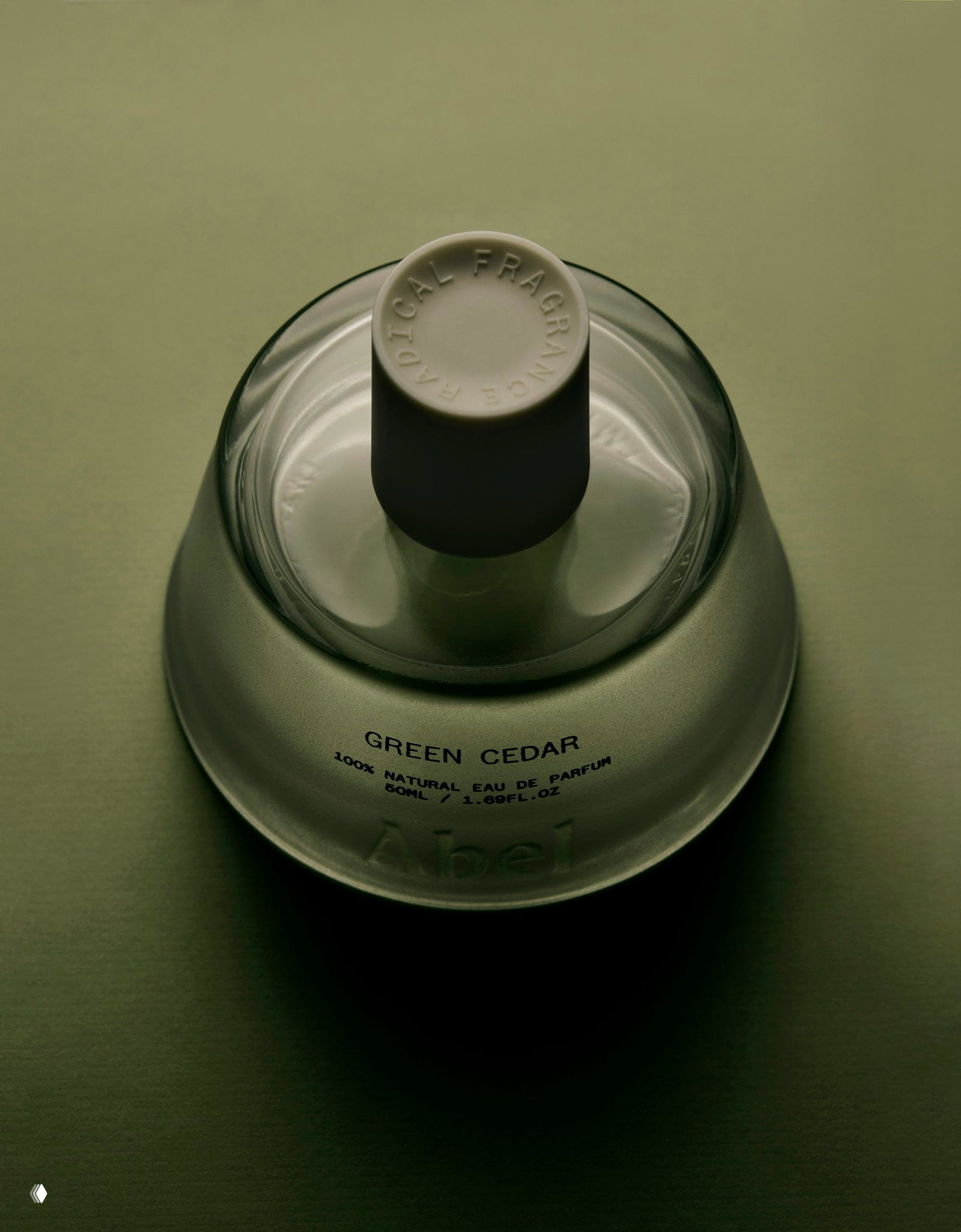 Вид сверху на флакон Abel: стеклянная горловина, матовая пробка и надпись GREEN CEDAR на тёмно‑зелёном фоне.