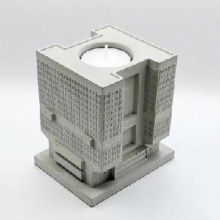 Кубическая бетонная миниатюра, выполненная как подсвечник: ниша для свечи и геометрически выверенный фасад в мелкой деталировке.