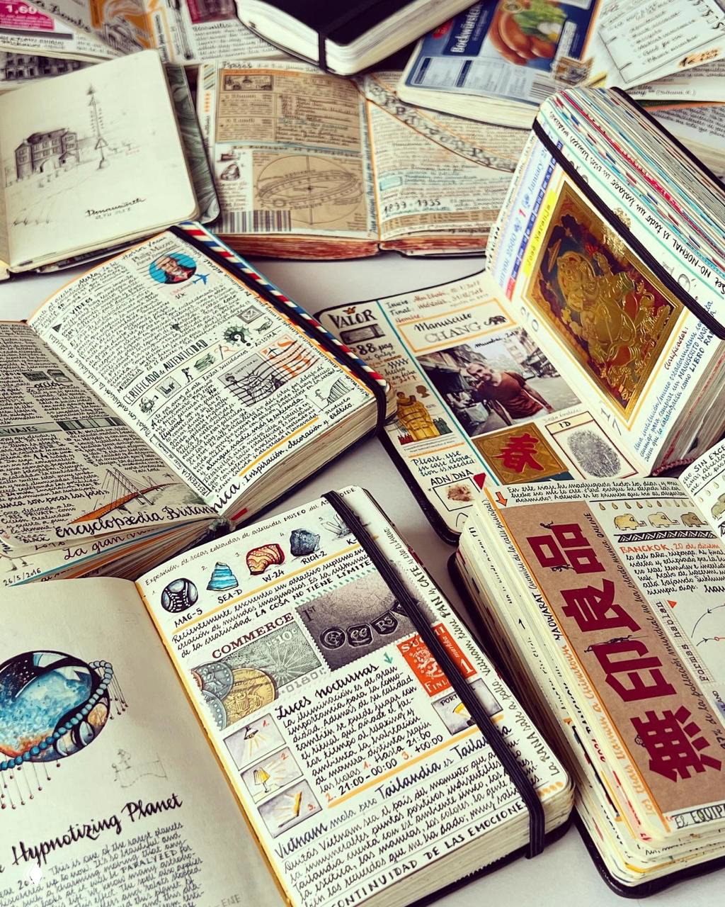 Несколько открытых записных книжек с плотно заполненными страницами: рисунки, стикеры, мини-иллюстрации и короткие заметки о поездках.