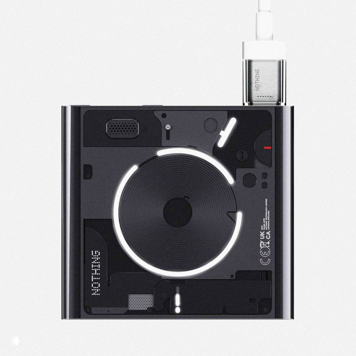 Вид сверху чёрного концепт‑плеера Nothing Npod с подключённым кабелем, видны элементы платы, логотип и подсвеченный центральный диск.