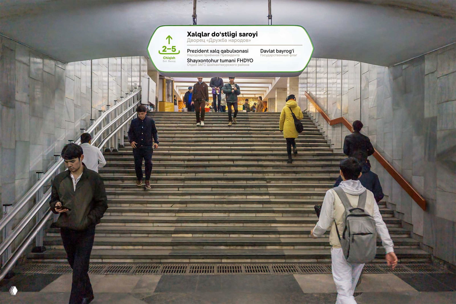Лестничный спуск в метро с подвесной табличкой «Xalqlar doʻstligi saroyi», люди поднимаются и спускаются по ступеням, пример обозначения выходов.