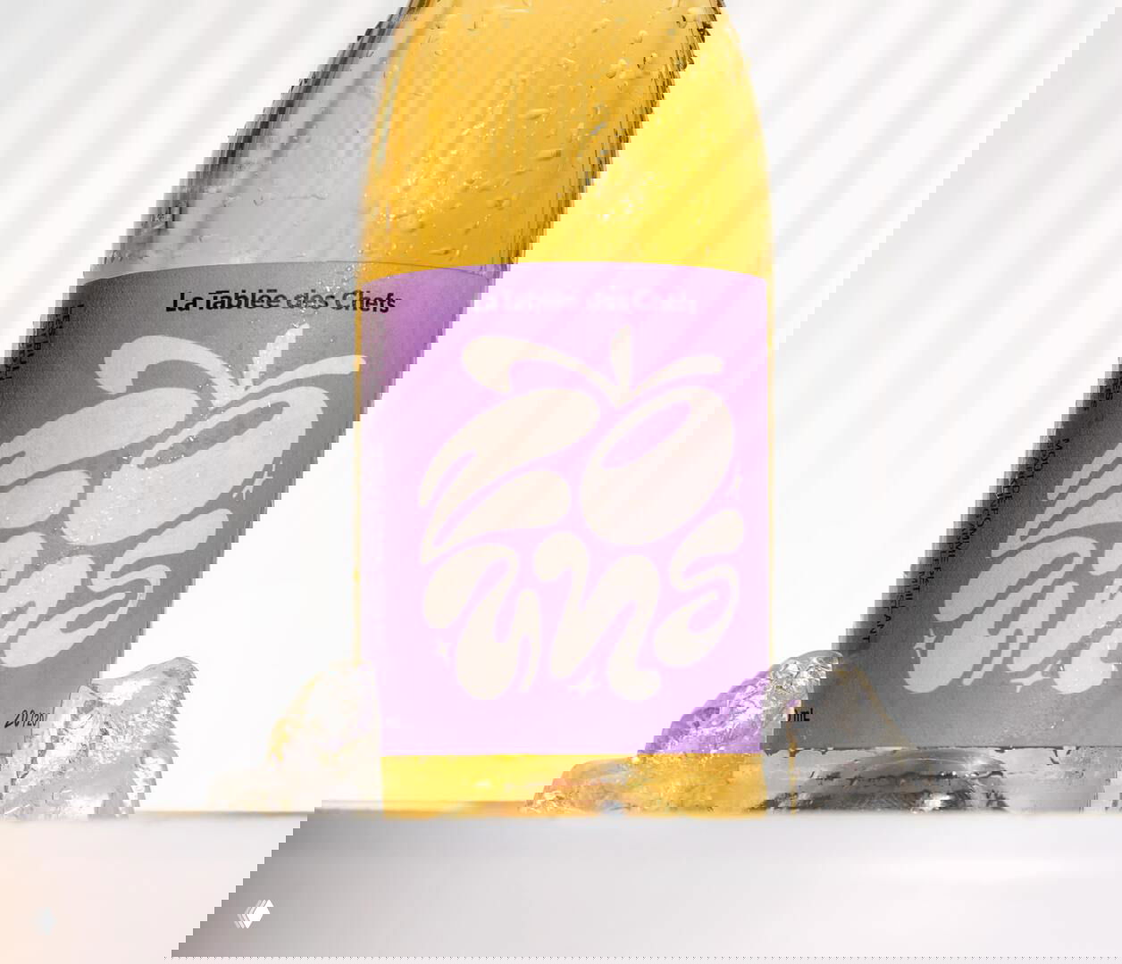 Крупный план бутылки сидра с фиолетовой этикеткой и графическим рисунком, капли конденсата на стекле, дизайн и фотография в стиле упаковки.