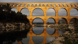 Фотография моста с рядом арочных пролётов и отражением в воде — визуальная отсылка к мотиву арок в логотипе Abridge.