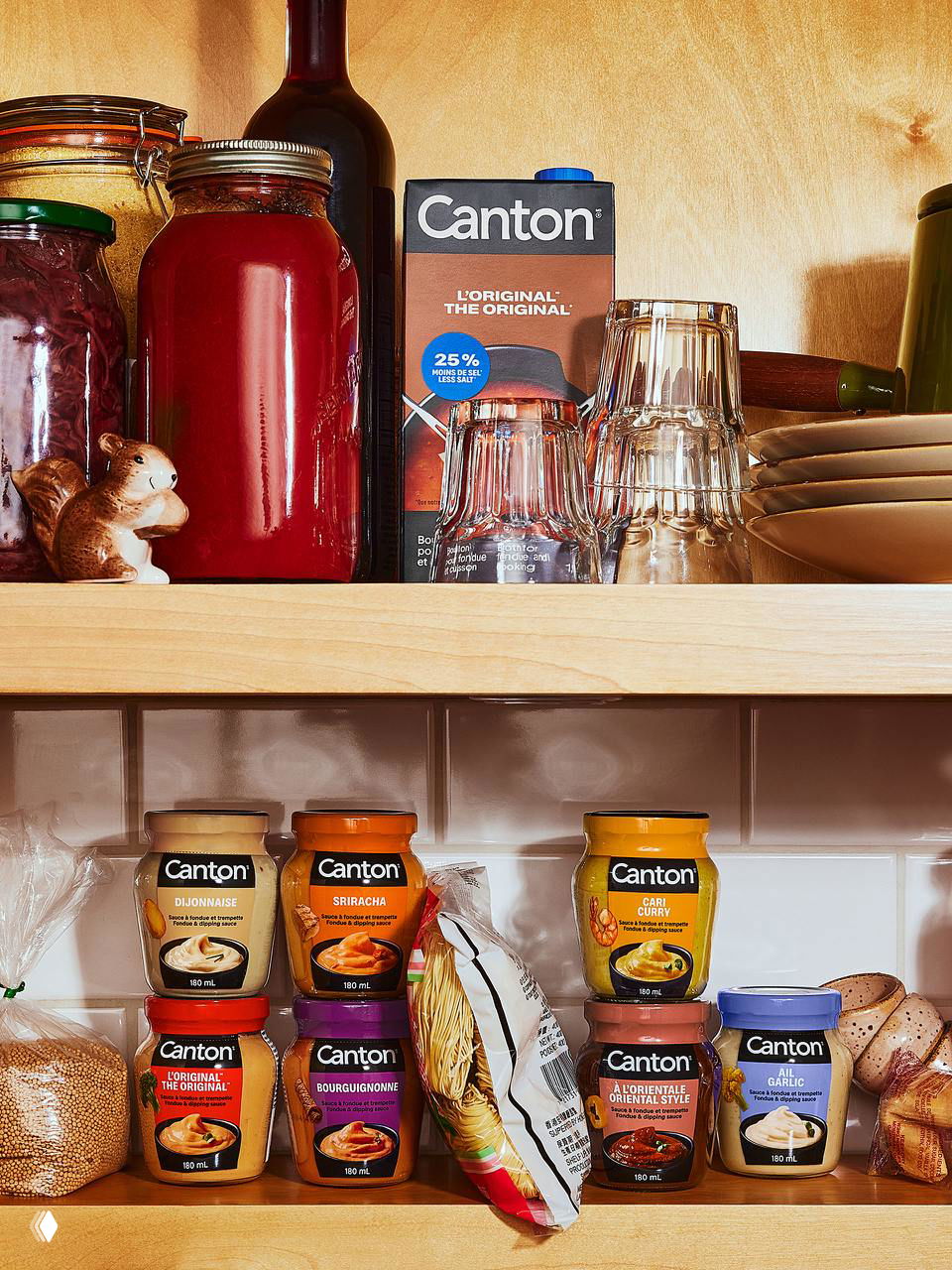 Полка с баночками Canton в бытовом интерьерном кадре: ряд банок и тетрапаков с обновлённым логотипом и цветовыми кодами вкусов.