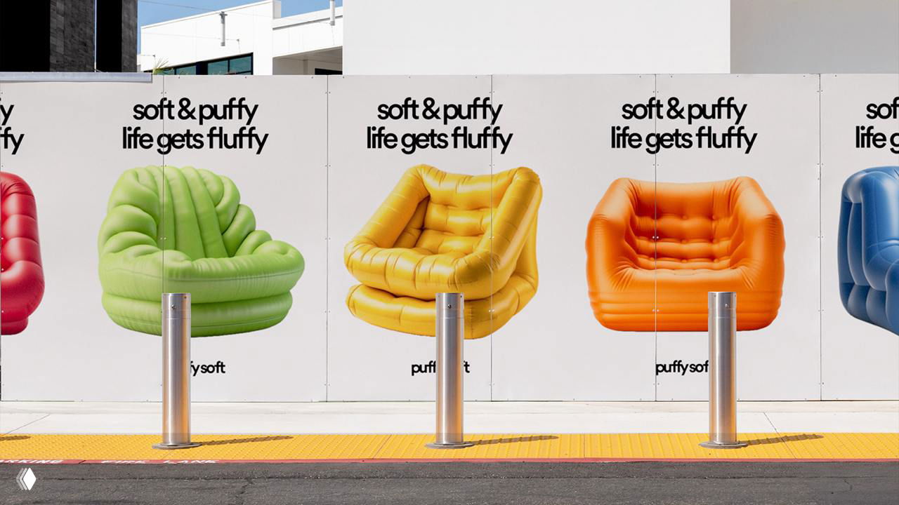 Уличные рекламные плакаты PuffySoft с разноцветными надувными креслами на конструктивном заборе; в кадре видны металлические столбики и городская среда.