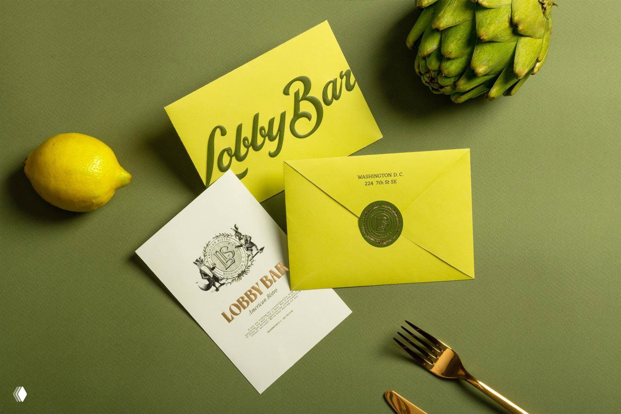 Верхняя съёмка меню и визитки Lobby Bar на зелёном фоне: кислотно‑жёлтая визитка рядом с ломтиком лимона и элементами фирменной графики.