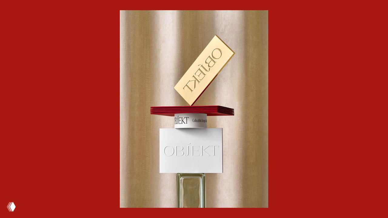 Композиция брэндинга OBJEKT: золотая карточка, стопка бордовых элементов и белая тиснёная вкладка на фоне шёлкового полотна, стилизованная под арт-объект.