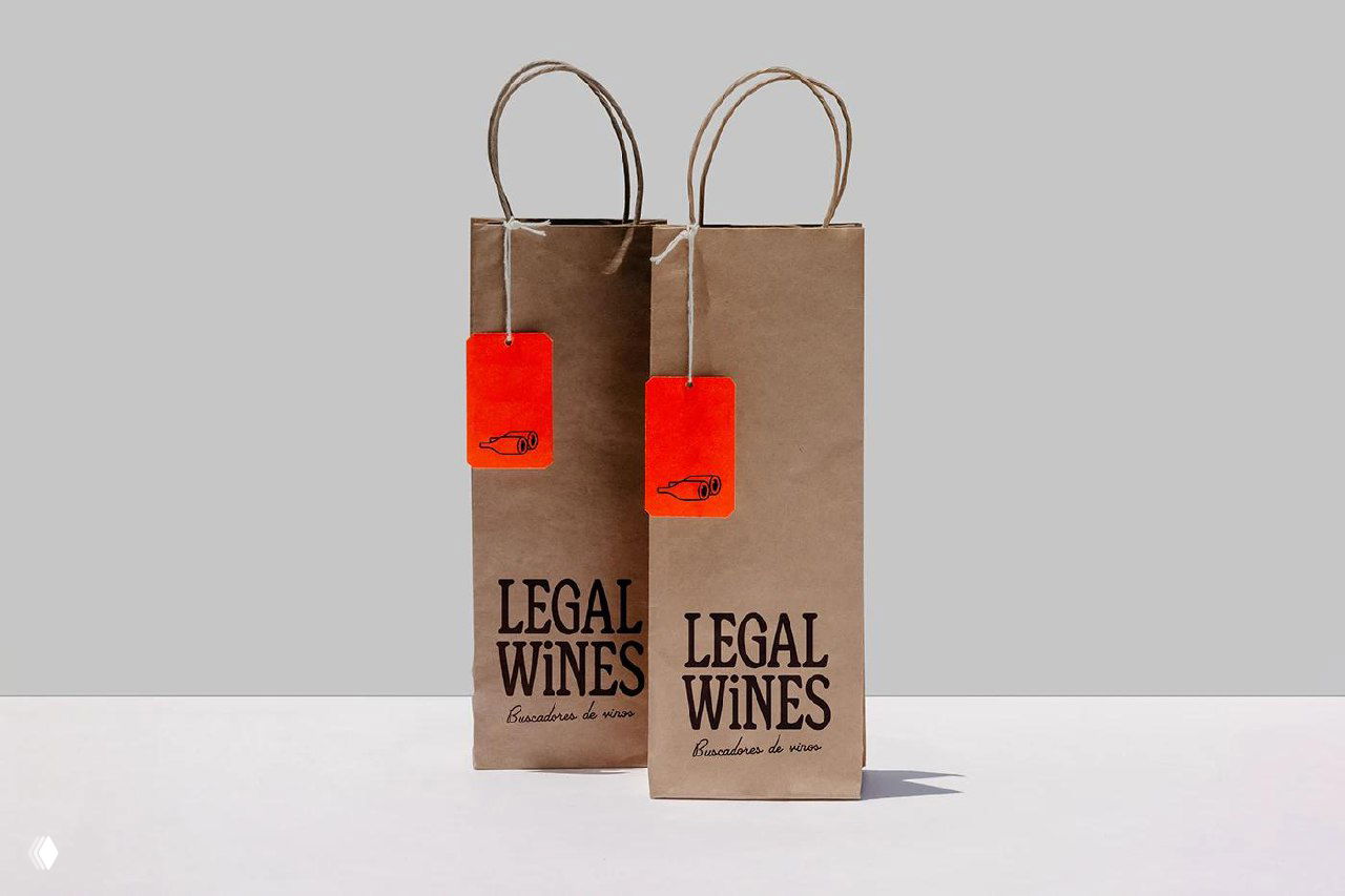 Фотография подарочных пакетов и подвесных бирок Legal Wines: бумажные пакеты, висящие ярко‑оранжевые бирки и строгая фирменная типографика бренда в концептуальной постановке.
