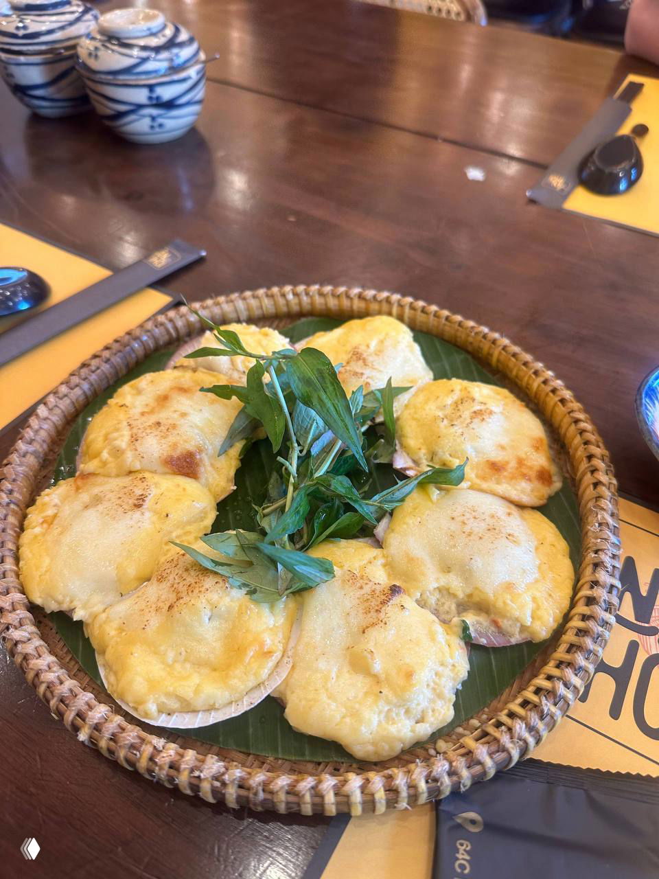 Традиционная закуска или горячее блюдо на бамбуковой подложке — несколько порционных сырных корочек на зелёных листьях