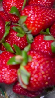 Крупный размытой план ягод клубники в макро-кадре, текстура красных ягод и зелёные хвостики, подчёркивающие сочность и свежесть урожая.