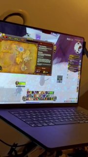 Экран ноутбука с игровым интерфейсом и картой (похоже на Warcraft), видна панель способностей и окно с настройками игры на столе