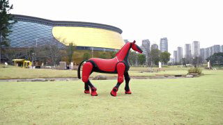 Красная роботизированная лошадь на травяном газоне у современного здания — демонстрация робота DEEP Robotics, собранного на базе M20 Pro