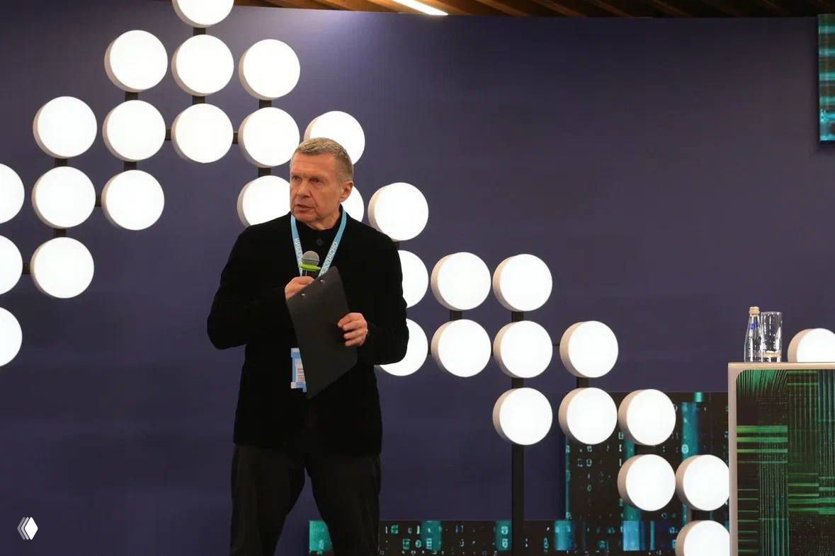 Владимир Соловьёв выступает на сцене форума с микрофоном и документами, позади декоративные круглые световые элементы — кадр с выступления