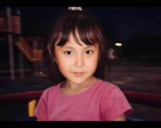 Кадр видео: близкий портрет ребёнка на карусели, мягкое освещение, серьёзный взгляд, ощущение вращения и размытия фона.