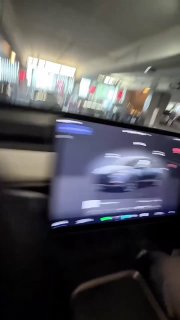 Размытый кадр из салона автомобиля Tesla: экран мультимедийной панели с интерфейсом автопилота и часть интерьера, съёмка изнутри во время поездки.
