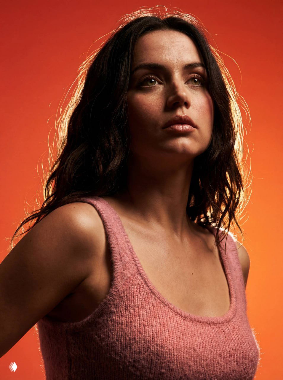 Средний крупный план женщины в фотореалистичном стиле на насыщенном оранжево‑красном фоне, с сильным обводящим светом и сохраненной текстурой кожи.