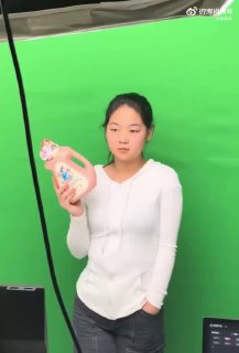 Девушка на фоне зелёного хромакея держит товарный флакон; кадр рекламной съёмки, иллюстрация применения ИИ для добавления речи, мимики и липсинка.