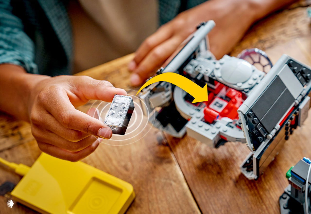 Рука держит прозрачный Smart Brick рядом с собранным набором LEGO; видна связь и индикация звуковых/световых эффектов в игровом контексте.