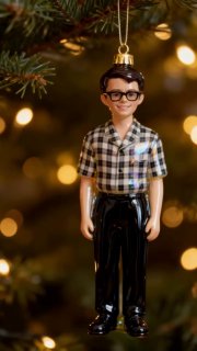 Миниатюрная стеклянная фигурка молодого человека в рубашке и очках, блестящая поверхность и праздничный размытый фон с огнями.