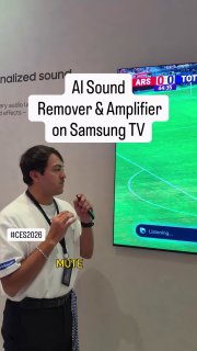 Демонстрация функции на стенде: человек с микрофоном рядом с телевизором, на экране футбольный матч и надписи про AI Sound Remover и усиление голоса.