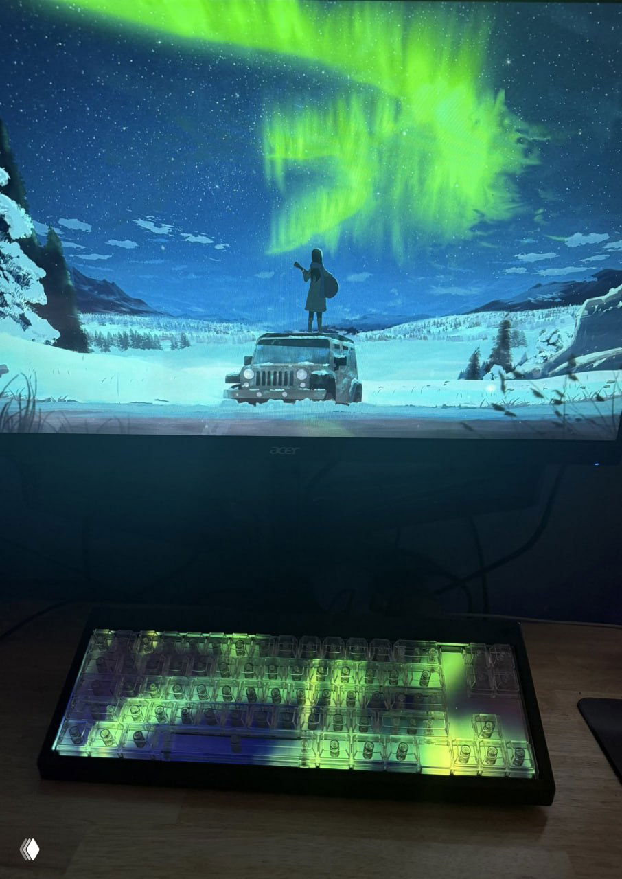 Клавиатура Centerpiece на фоне монитора, на котором зелёно-голубое северное сияние; на кейкапах отображаются цветовые анимации видео-скинов.