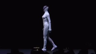 Гуманоид XPeng в полный рост на сцене презентации: белая форма робота на тёмном фоне, видно очертания корпуса и туловища.