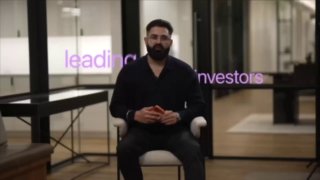 Кадр промо-видео Lotus Health AI: мужчина в офисе на фоне интерьера и титров, нейтральная сцена, иллюстрация запуска цифрового ИИ-врача.