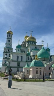 Панорамный вид на Ново-Иерусалимский мужской монастырь с золотыми куполами и белыми фасадами на фоне голубого неба в солнечный день.
