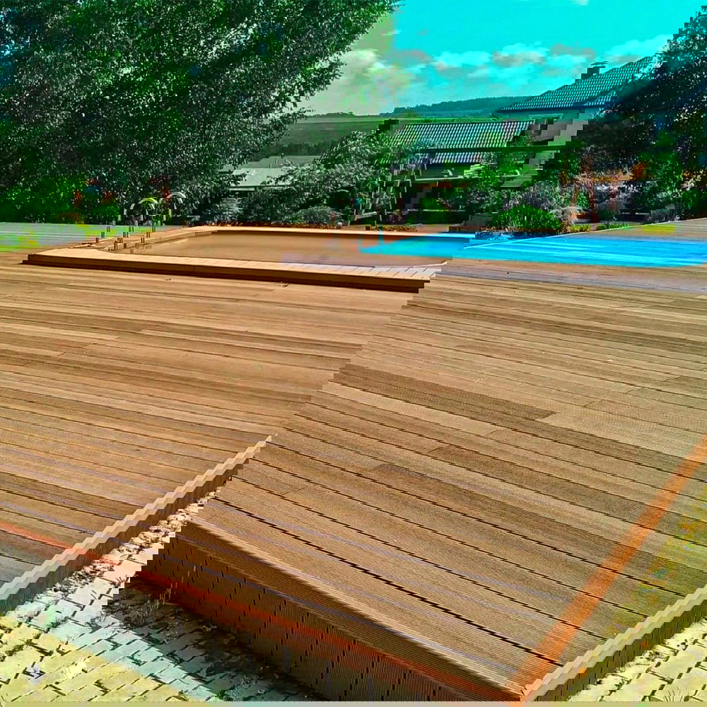 Большой открытый настил вокруг бассейна из тёмно-коричневой террасной доски ДПК, аккуратно уложенные планки композита.