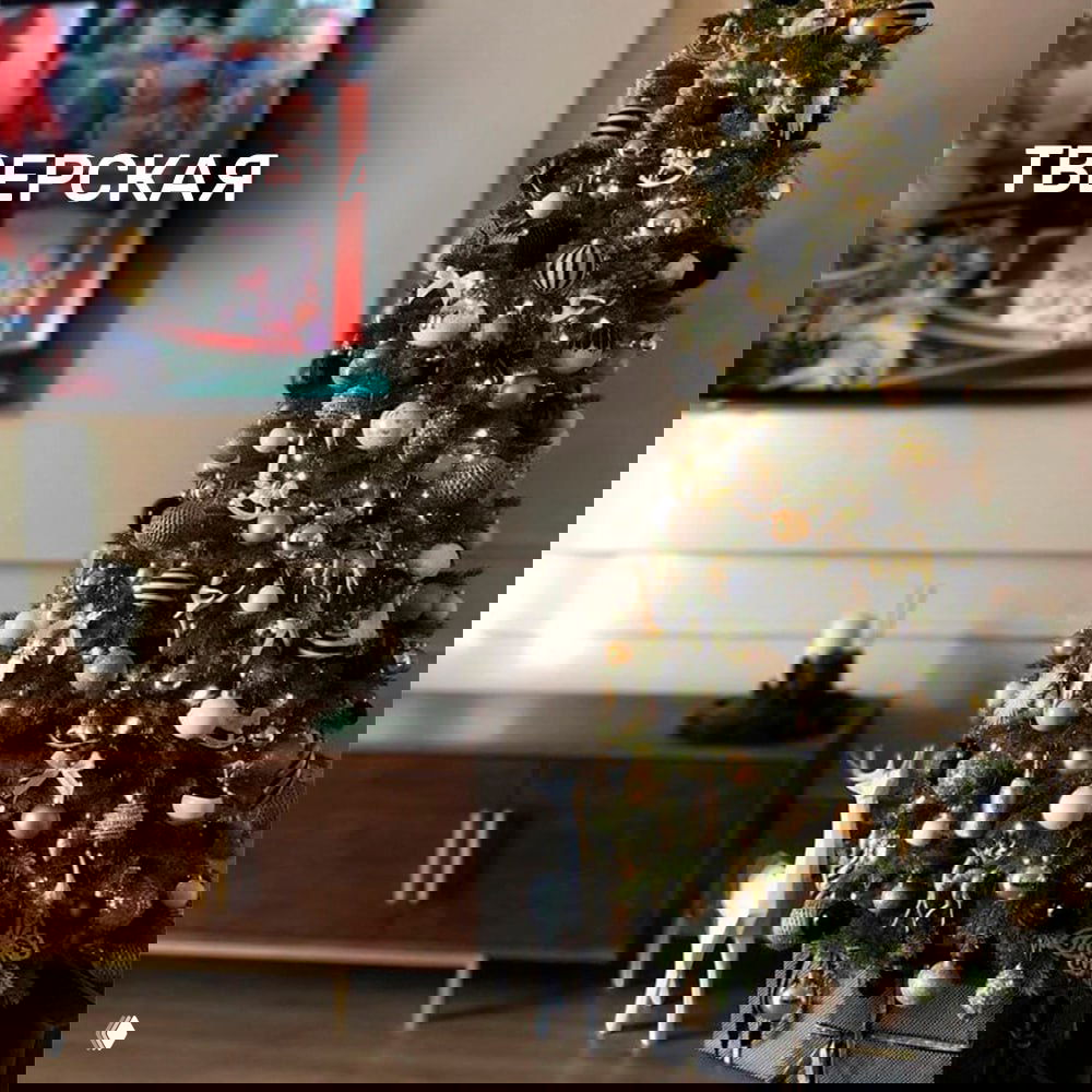 Пышная украшенная ёлка модели Тверская с золотыми и чёрными игрушками в уютной гостиной, демонстрация плотной, но компактной формы.