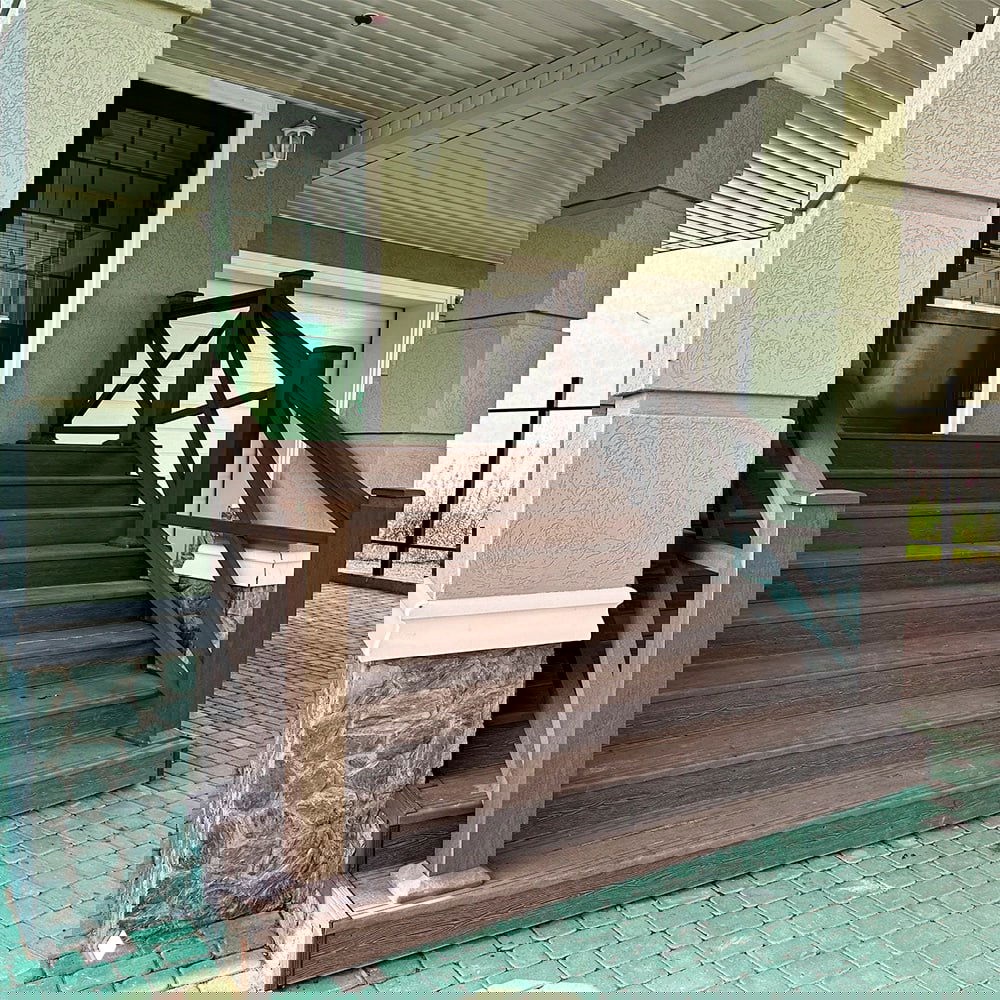 Крыльцо с лестницей, облицованной ДПК: ступени и перила выполнены из коричневого древесно-полимерного композита, прочная отделка у входа.