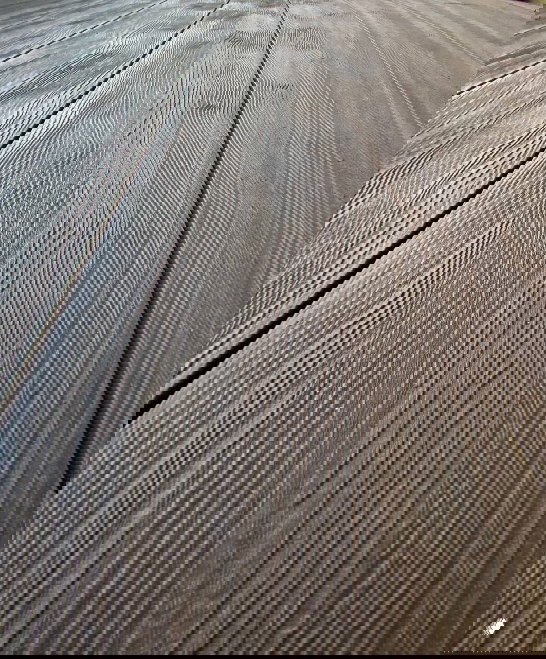 Крупный план текстуры террасной ДПК‑доски: выраженная древесная фактура, рифлёная поверхность и швы между планками.