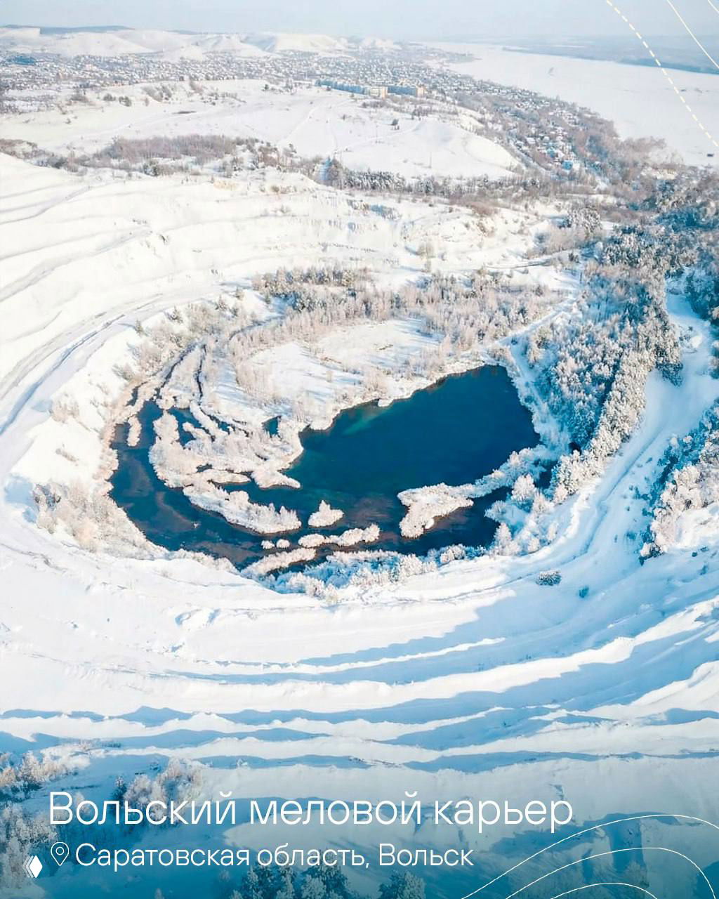 Вольский меловой карьер: круговое озеро в глубине карьера, заснеженные террасы и ледяные берега, вид сверху с воздушного ракурса.