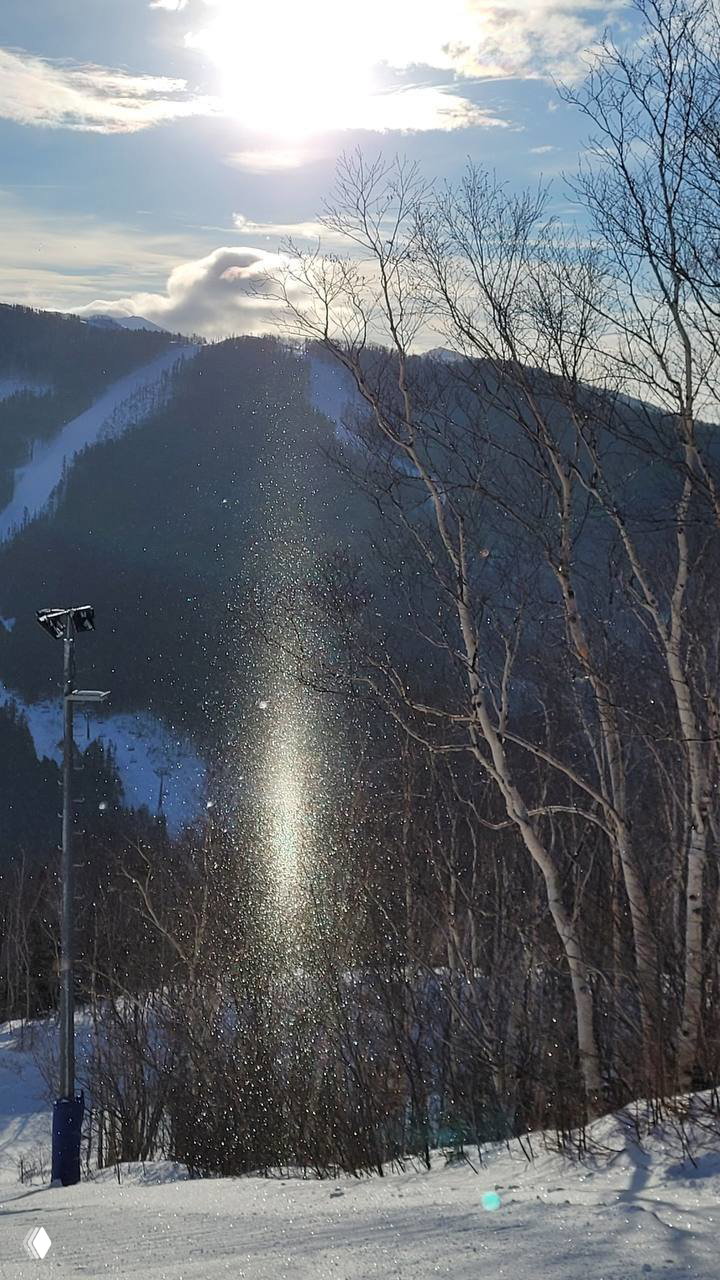Вертикальный блестящий столб из ледяных кристаллов и отражённого света под солнцем, снятый с горнолыжного склона на Сахалине.