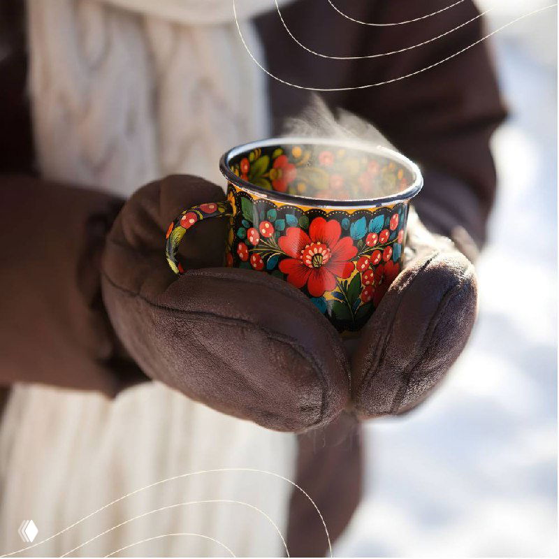 Крупный план горячего напитка в кружке с полхово-майданским орнаментом и рук в тёплых перчатках — атмосфера уюта в холоде