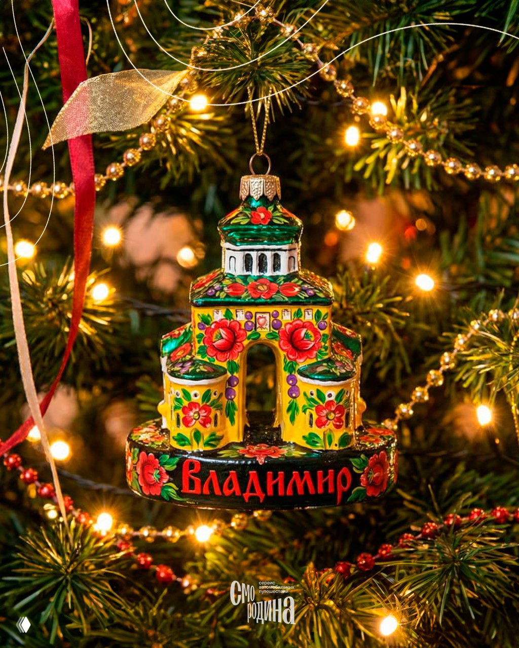 Ёлочная игрушка с яркой полховско‑майданской росписью и надписью «Владимир», висящая на рождественской ёлке с тёплой гирляндой огоньков.