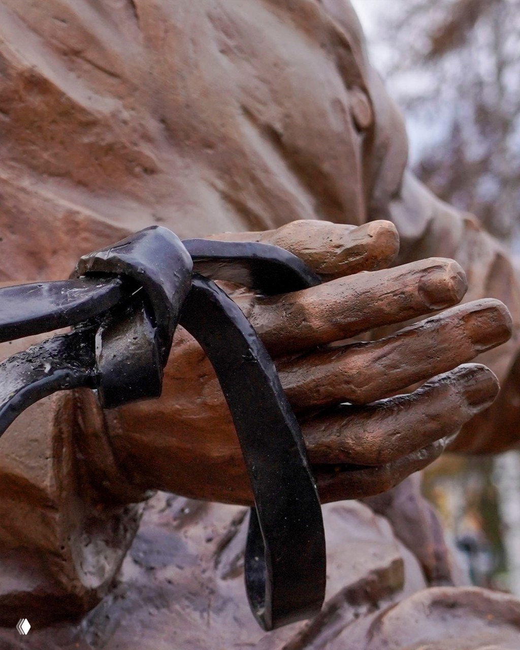 Крупный план бронзовых рук скульптуры ямщика с упряжью — акцент на деталях и фактуре металла в условиях пасмурного дня