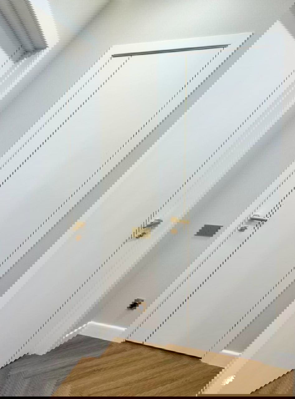 Крупный план дверной группы Лайн 12: тонкая золотая декоративная вставка по кромке двери и комплект золотых ручек на белом фоне.