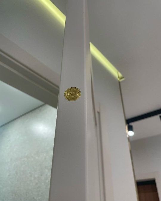 Крупный план кромки двери Дивайн 6: матовое покрытие, аккуратная кромка и маленькая золотистая фирменная наклейка салона Geona на торце двери.