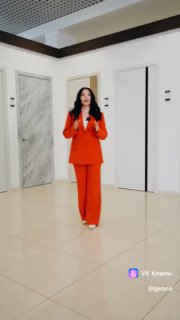 Женщина в оранжевом костюме в шоу-руме GEONA на фоне выставочных дверей; показ моделей и интерьерного оформления.