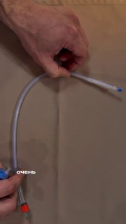 Руки специалиста показывают устройство и манипуляцию с катетером Фолея на нейтральном фоне — обучающая демонстрация для беременных о процедуре.