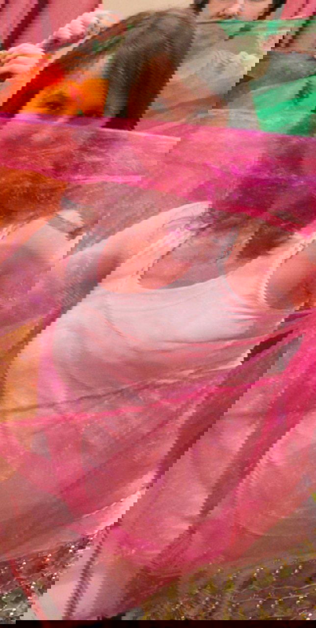 Беременная женщина в полупрозрачном розовом шарфе выполняет движения: практика для релаксации, подготовки к родам и снижения стресса.