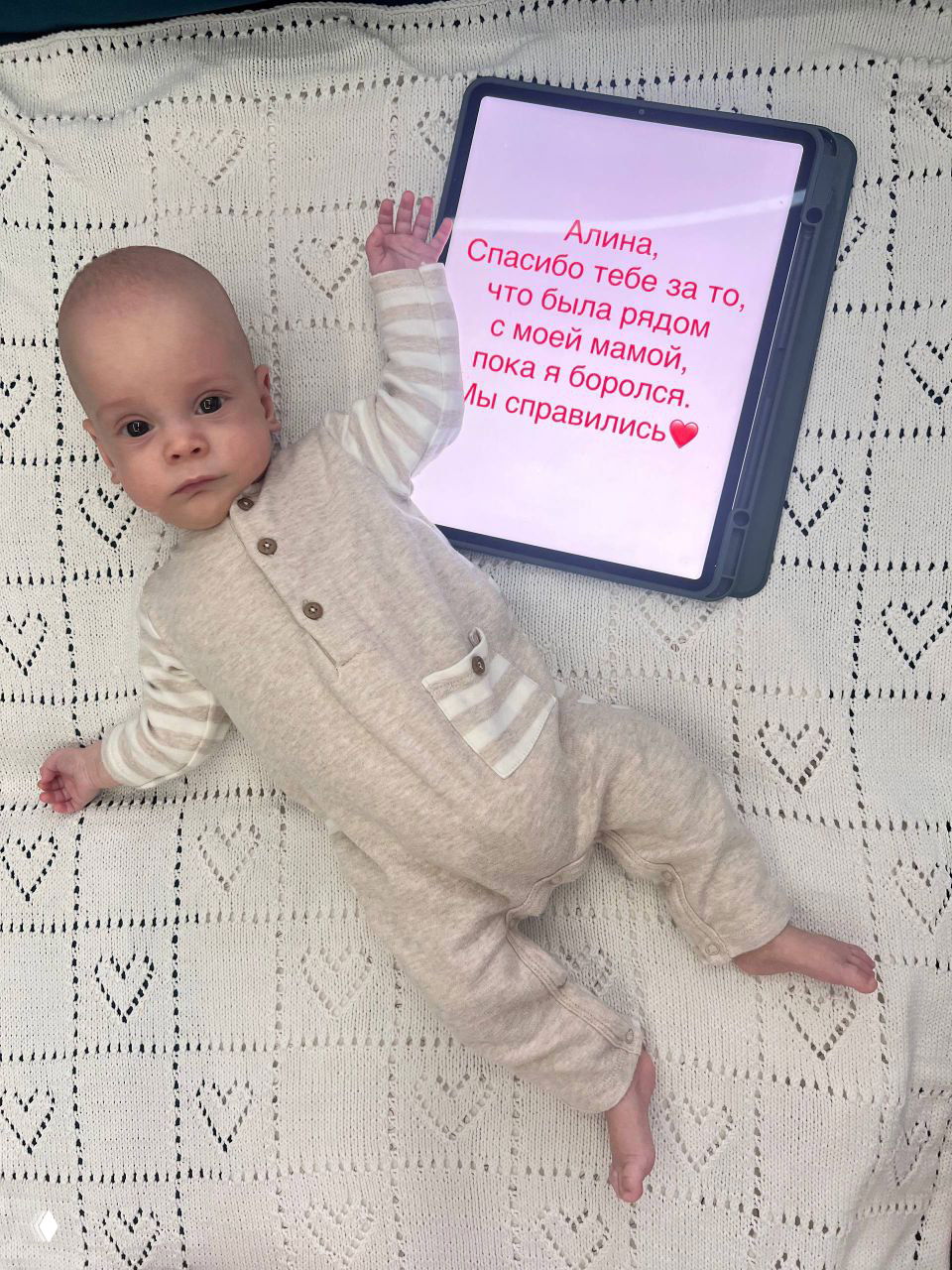 Портретный снимок Вани в светлом комбинезоне на пледе: спокойное лицо, открытые глаза и ощущение восстановления после непростой истории рождения.