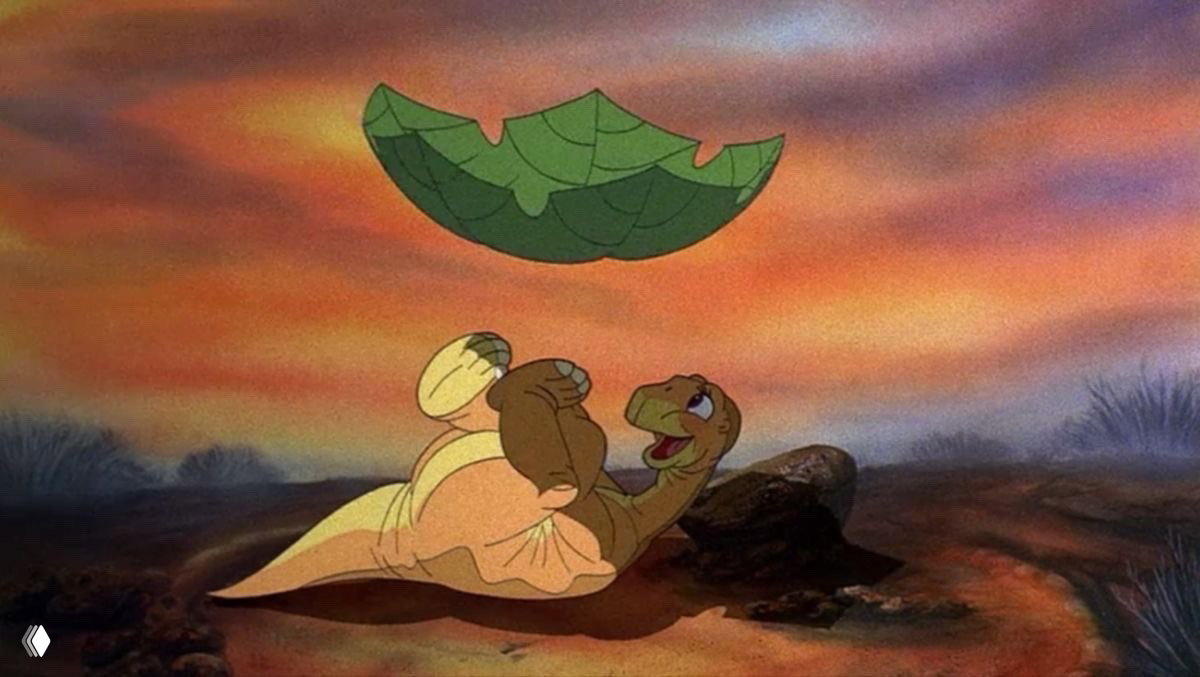 Светлый кадр: молодой динозавр лежит под большим листом и смеётся, тёплый свет заката подчёркивает добродушие персонажа и атмосферу уюта.