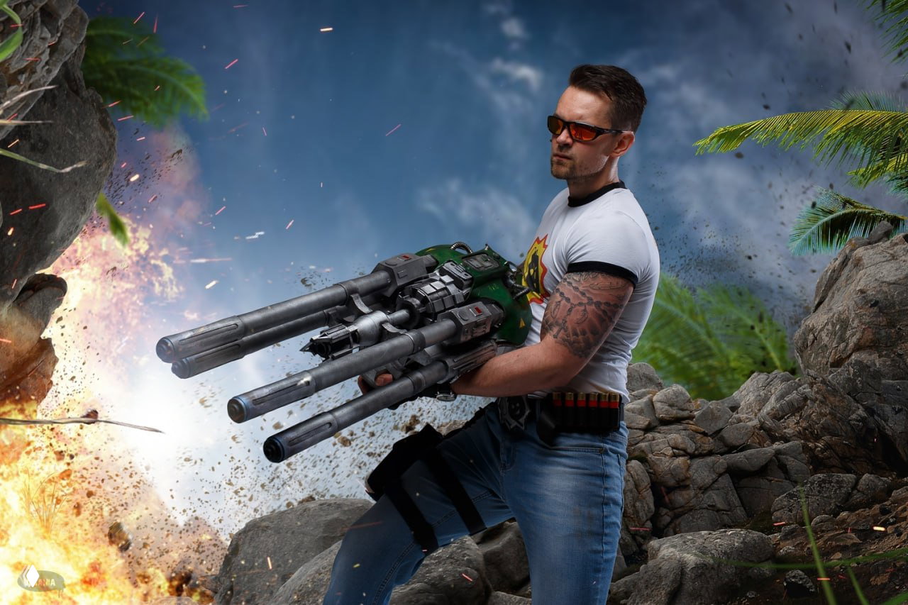 Косплей Serious Sam в динамической позе: мужчина держит крупнокалиберное фантастическое оружие, вокруг эффектные вспышки и пыль пустыни.