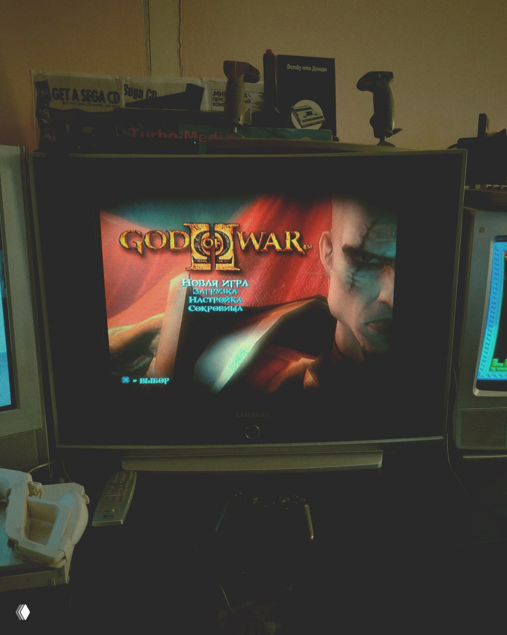 Рука посетителя держит классический джойстик NES на фоне работающего CRT-телевизора с изображением ретро-игры и картриджами рядом.