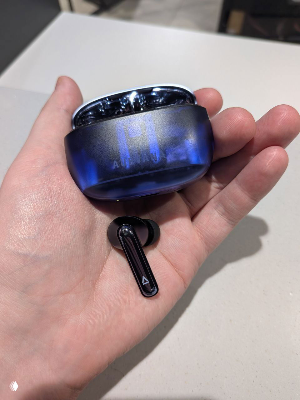 Ладонь держит футляр с сине-фиолетным переливом и отдельный вкладыш на ладони — акцент на дизайне корпуса и накладке.